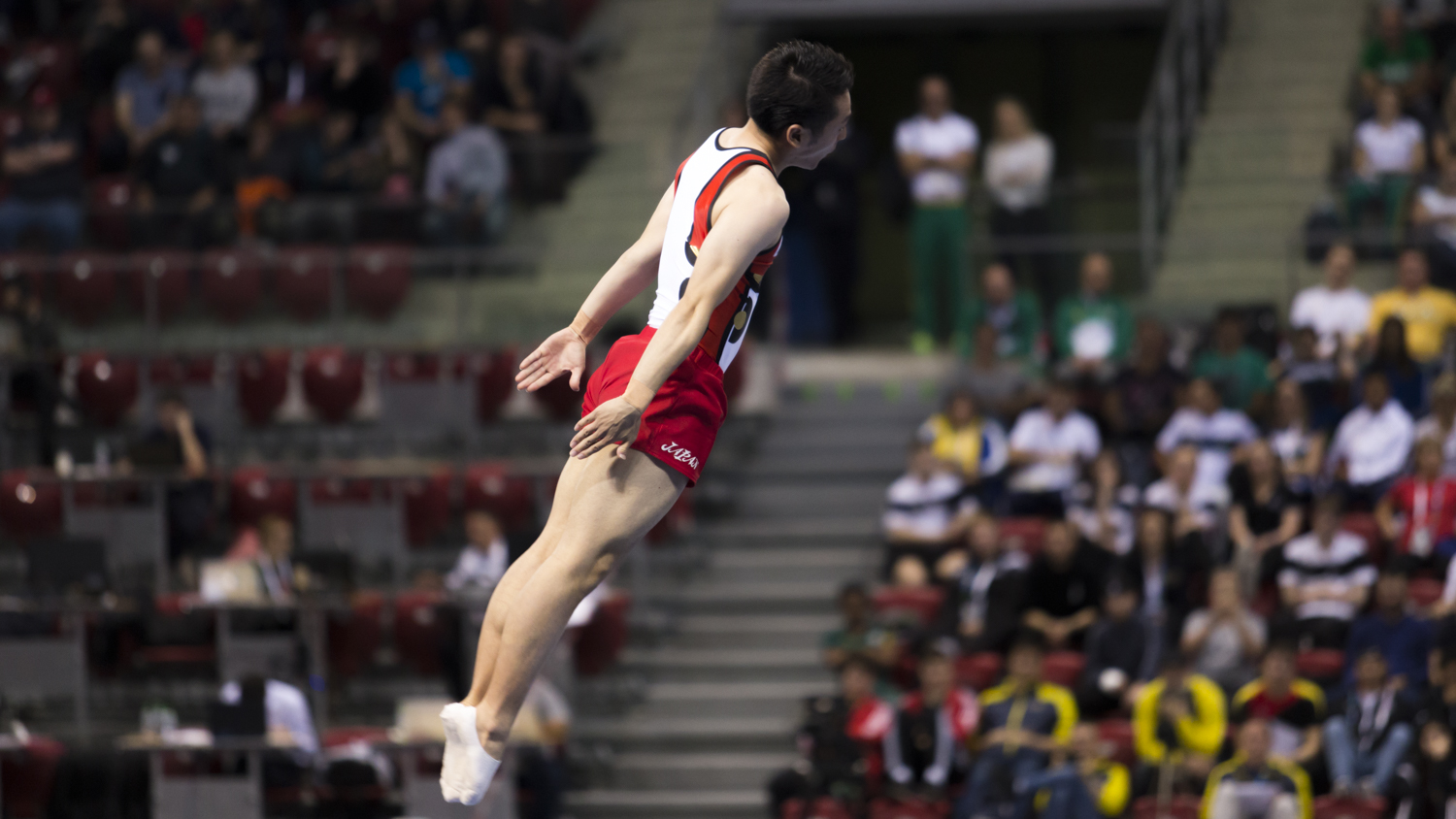 Photographie couleur du trampoliniste Kisho Daiki concourant pour le Japon en position de salto tendu