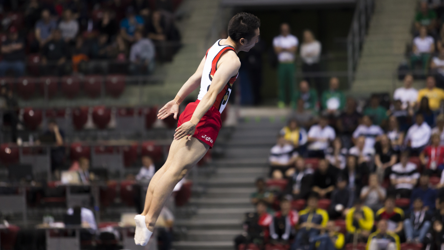 Photographie couleur du trampoliniste Kisho Daiki concourant pour le Japon en position de salto tendu