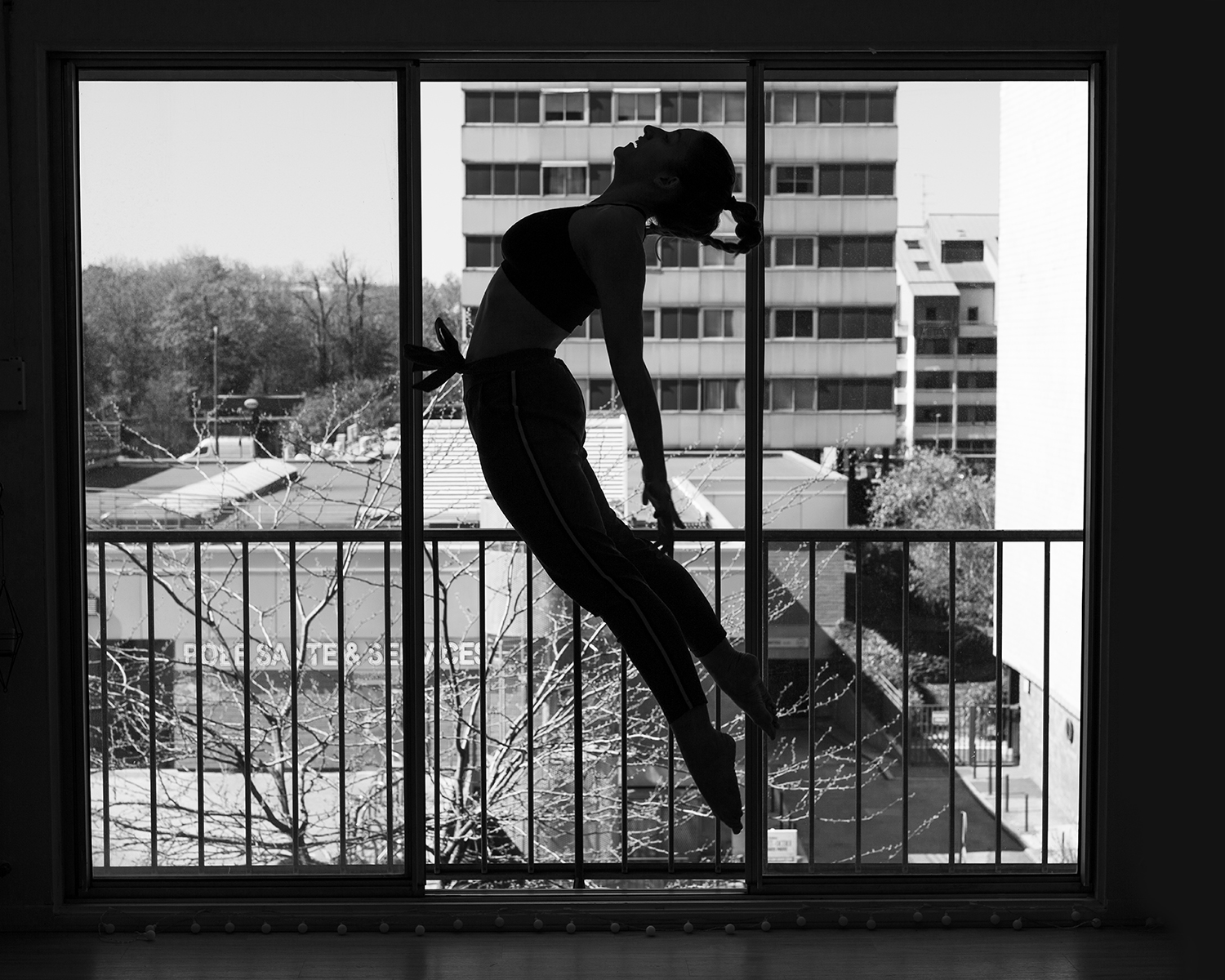 Photographie en niveau de gris de Cécile Reiter qui danse au milieu d'une route dans une forêt du Jura