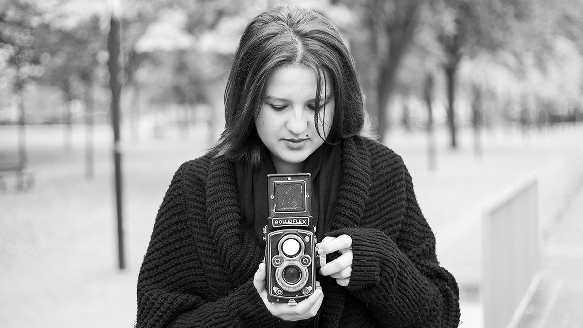 Photographie en niveau de gris d'une femme portant un appareil photo argentique