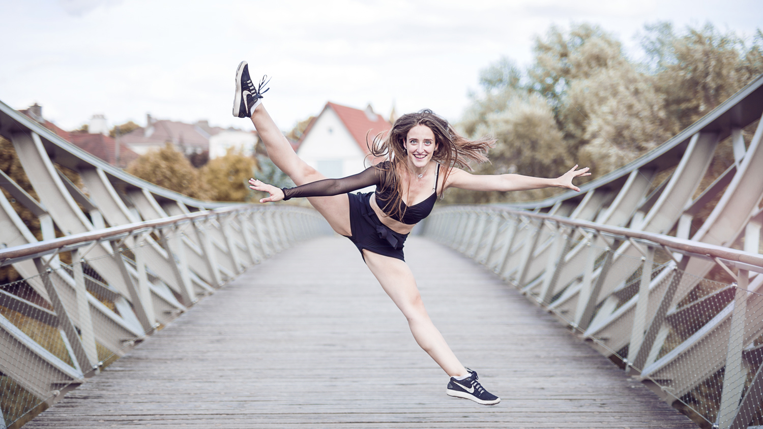 Photographie couleur de Cécile Reiter, danseuse, qui effectue un saut écart sur la passerelle du Graoully à Metz